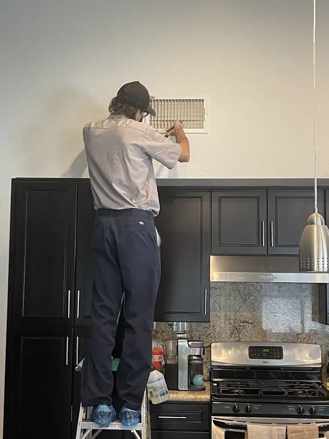 Technician inspecting an air vent during HVAC service in Gray